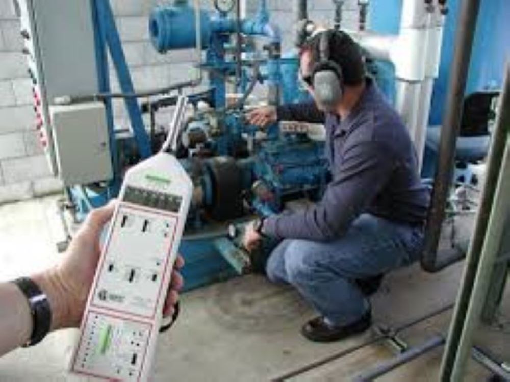 An Industrial Hygienist operating machinery while being monitored.