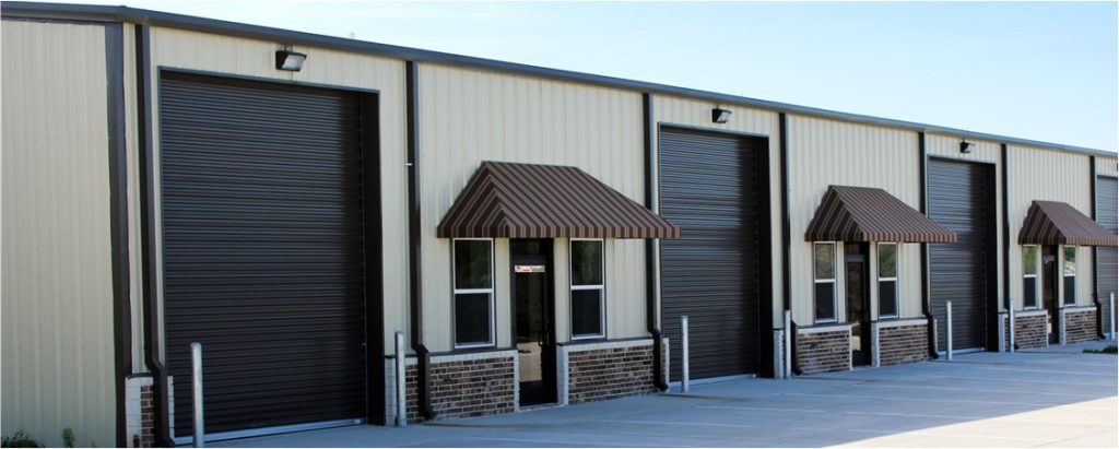 Exterior view of warehouse with large garage door and a sign reading "RW Specialty Imports" on the entrance.